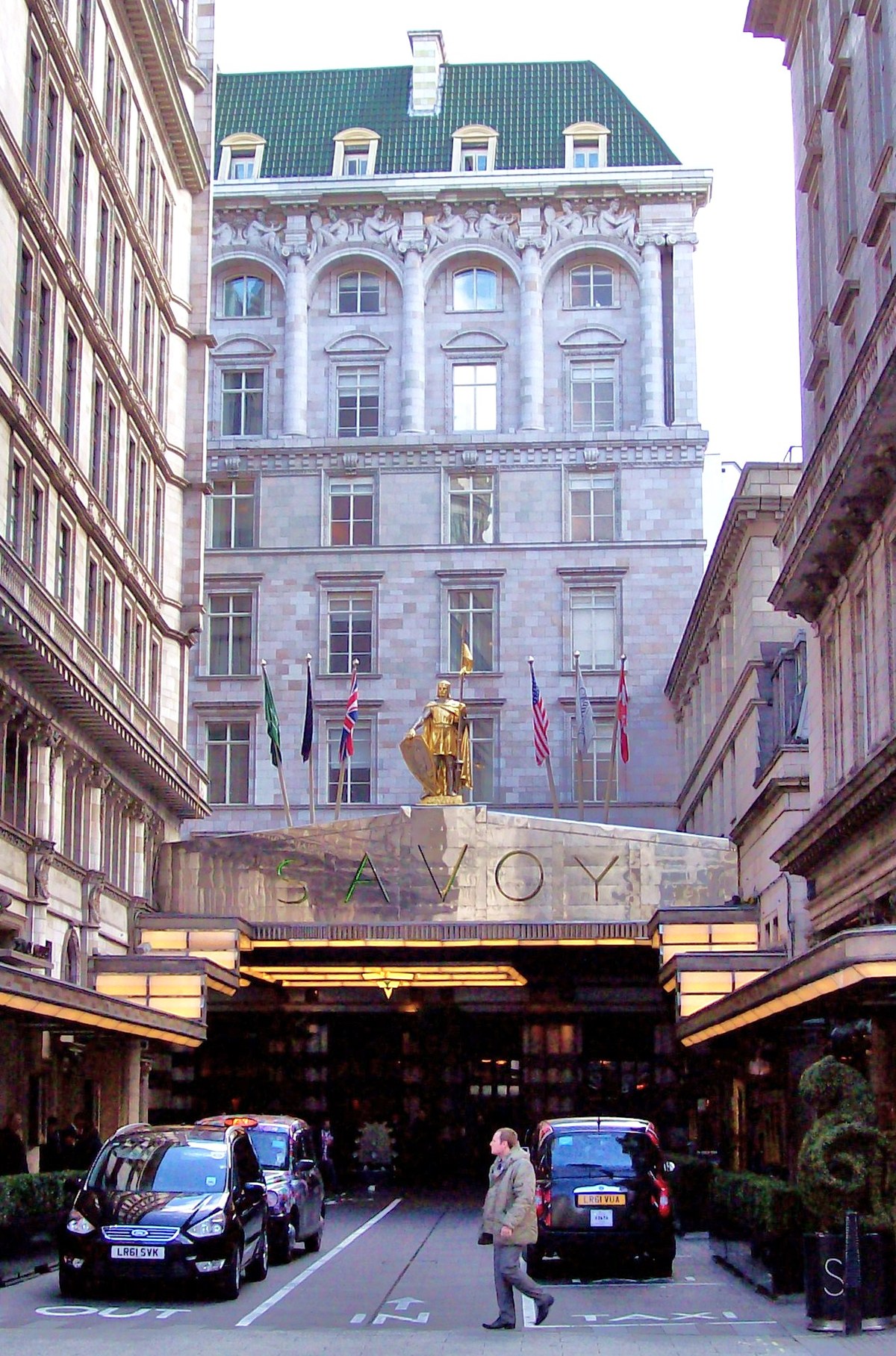 Вход в лондонский отель Savoy: вывеска SAVOY, золочёная фигура рыцаря над козырьком, чёрные такси