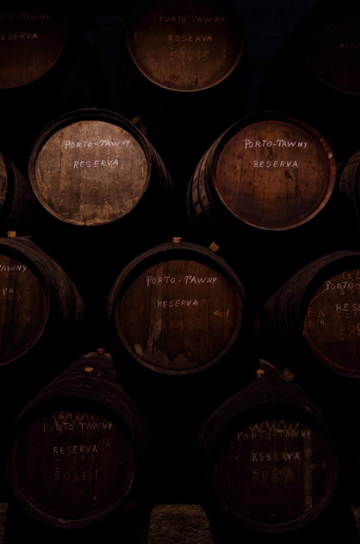 Тёмный погреб: штабель дубовых бочек, на торцах мелом надписи PORTO-TAWNY RESERVA и номера партий