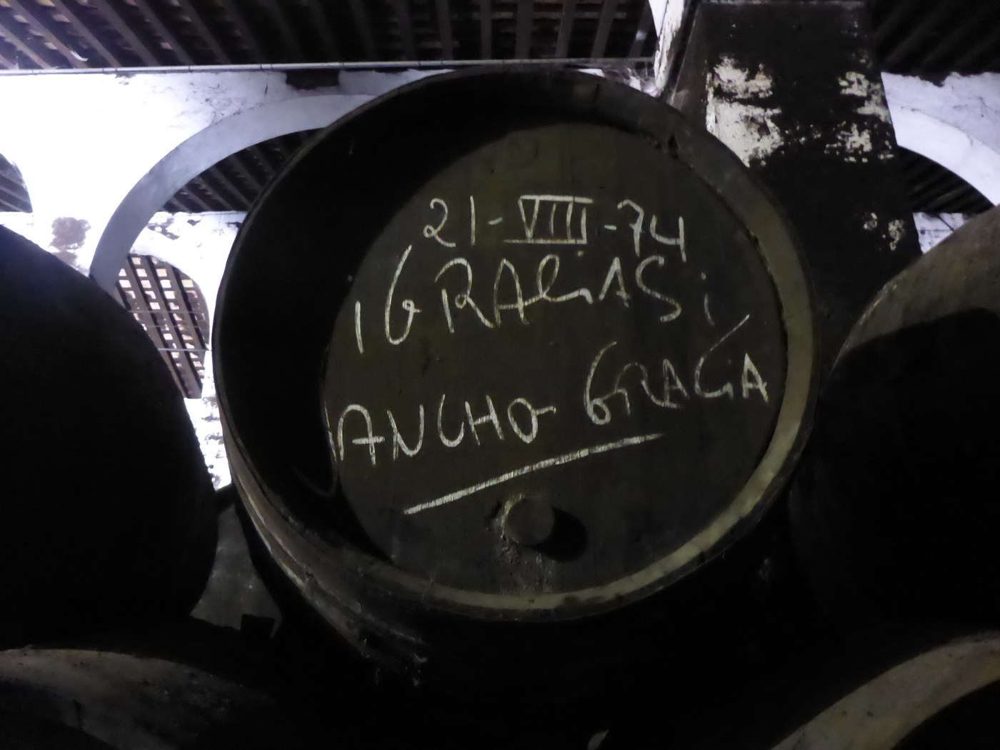 Торец большой дубовой бочки в тёмном погребе, по донцу мелом написаны дата и имена